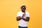 Stylish young african american man holding cup of take away coffee isolated over yellow background.