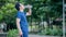 A stylish young Asian man drinking water from a plastic bottle after exercising in a park wearing white headphones. Athletes