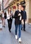 Stylish young business woman in casual dress walking through city street in crowd of people