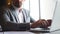 Stylish young businessman in a grey suit typing on laptop