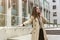 Stylish young businesswoman wearing smart outfit catching taxi in the middle of the street, looking gorgeous, style and beauty