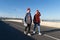 Stylish young couple of male and female walk together on bridge after longboard skating on bridge