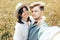 Stylish young family taking photo in travel and enjoying hiking on top of mountain in wildflower meadow. Summer vacation. Happy