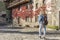 Stylish young female walking with jeans jacket and backpack in beautiful old medieval village.Traveling background with copy space