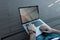 Stylish young freelancer man in blue jeans in sneakers is typing on a metal modern laptop in a room. Guy works