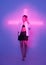 Stylish young girl fashion model posing in neon light on violet studio background with pink cross