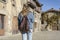 Stylish young girl walking with fashion jeans jacket and backpack in old medieval village