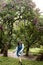 Stylish young girl walking in the garden of blossoming lilacs