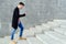 Stylish young man in plaid shirt and jeans walking up stairs.