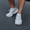 Stylish young man stands on a metal road in sports white sneakers. Fashionable men`s shoes. Street casual style. Close-up