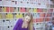 Stylish young woman choosing color of hair dye from palette in shop