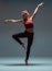 Stylish young woman dancing barefoot in studio isolated on gray background. Dance school poster