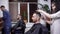 A stylish and young woman hairdresser takes a hair trimmer in her hands and begins to make hair styling and haircut for