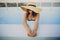 Stylish young woman in hat relaxing in blue pool and enjoying summer holiday. Summer tropical vacation. Girl in sunhat on vacation