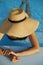 Stylish young woman in hat relaxing in blue pool and enjoying summer holiday. Summer tropical vacation. Girl in sunhat on vacation