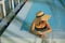 Stylish young woman in hat relaxing in blue pool and enjoying summer holiday. Summer tropical vacation. Girl in sunhat on vacation