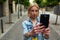 Stylish young woman photographing urban view with mobile phone camera during summer journey