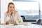 Stylish young woman sitting at table in office