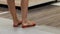 Stylish young woman stands in sandals waiting on the tiled floor in the store.