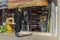 Stylishly dressed iranian woman in black hijab passes by fabric stores in the eastern bazaar