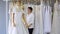 Stylist asian woman adjust and choosing the best white wedding dress in fashion cloth wedding studio.