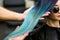 Stylist demonstrates his work with Beautiful girl. Barber haircut dyed hair color blue