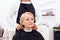 Stylist dresses hairdressing collar on mature woman`s neck. Female haircut.