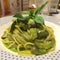 Stylist food, Close up Italian pasta spaghetti homemade green pesto sauce, mushroom top with basil leaf on white plate with blur r