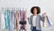 Stylist or personal assistant. Smiling african american woman holding packages and shows on clothes rack to web camera