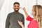 Stylist woman applying make up to handsome hispanic model at photo shoot backstage, getting ready for professional photoshoot