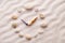 Stylized dial clock pebble and shells arrows on the sand for concentration and relaxation for harmony and balance
