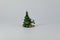 Stylized green Christmas tree and looking out from behind it snowman, subject shooting on a dark and light background.