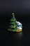 Stylized green Christmas tree and looking out from behind it snowman, subject shooting on a dark and light background.