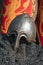 Stylized metal helmet and chainmail of an ancient Russian warrior on the background of a decorative red military shield.