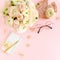 Stylized, pink women`s home office desk. Workspace with bouquet ranunculus and roses, clipboard on pink background. Flat