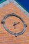 Stylized round clock on brick wall of building faÃ§ade with coni