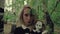 Stylized shot creepy white faced woman with a doll in the grass in the woods