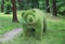 Stylized statue of a bear made of green plastic needles imitating grass