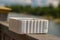 A styrofoam bait worm container on a ledge next to a lake ready to be used for fishing. blurred background and