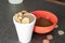 Styrofoam cup full of coins with red bowl of instant coffee
