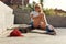 Subculture. Skater Girl Sitting On Concrete Ramp At Skatepark. Teenager In Casual Outfit Posing Outdoor.