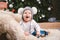 Subject children christmas new year. Caucasian little funny baby boy 1 year old sitting sleigh bear skin Christmas tree head warm