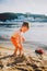 Subject construction and heavy industry. Abstraction child boy playing on the sand near the river in the summer toy red tractor