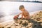 Subject construction and heavy industry. Abstraction child boy playing on the sand near the river in the summer toy red tractor