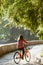 Subject ecological bicycle transport. Young Caucasian woman riding on a dirt road in a park near a lake renting an orange-colored