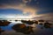 Submerged rocks in the sea under red skies