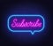 Subscribe neon text in a speech bubble frame on a brick wall background.