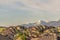 Suburb scenery with aerial view of roof of homes against snowy mountain and sky