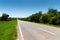 Suburban empty road asphalt surrounded by trees and grass. The concept of transportation and travel. Background green