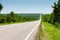 Suburban empty road asphalt surrounded by trees and grass. The concept of transportation and travel. Background green